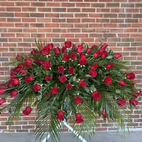 Casket spray of red roses with palm and fern greenery